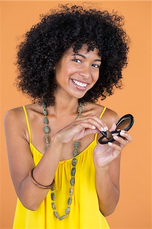 simsearch:6108-05869249,k - Portrait of a smiling woman doing make-up Stock Photo - Premium Royalty-Free, Code: 6108-06905354