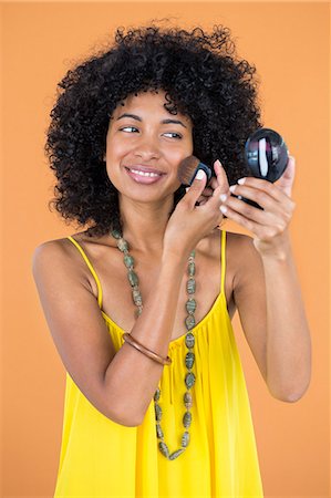 simsearch:6108-05869249,k - Smiling woman applying make-up on her face Stock Photo - Premium Royalty-Free, Code: 6108-06905384