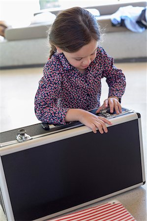 Girl trying to close a suitcase Stock Photo - Premium Royalty-Free, Code: 6108-06905321