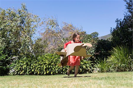 Girl playing with a cardboard airplane in lawn Stock Photo - Premium Royalty-Free, Code: 6108-06905339