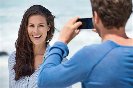 simsearch:6108-06907036,k - Man taking a picture of his wife with a cell phone on the beach Stock Photo - Premium Royalty-Free, Code: 6108-06905466