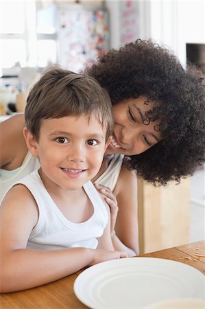 edad escolar primaria - Portrait of a smiling boy sitting with his mother at a dining table Foto de stock - Sin royalties Premium, Código: 6108-06905589