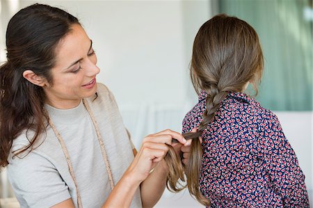 single mom - Smiling woman braiding her daughter's hair Stock Photo - Premium Royalty-Free, Code: 6108-06905624