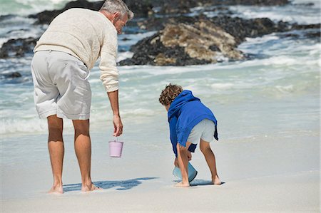 senior man grandchild - Boy playing with his grandfather on the beach Stock Photo - Premium Royalty-Free, Code: 6108-06905906