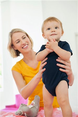 Smiling woman playing with her baby on the bed Stock Photo - Premium Royalty-Free, Code: 6108-06906065