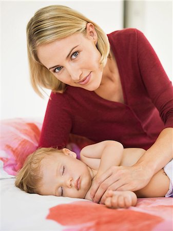 Woman reclining beside her baby sleeping on the bed Stock Photo - Premium Royalty-Free, Code: 6108-06906069