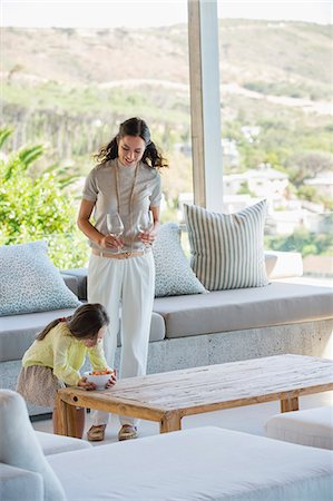 put on a table - Girl putting a bowl of snacks on a table beside her mother holding glasses Stock Photo - Premium Royalty-Free, Code: 6108-06906034