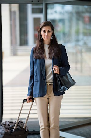 Businesswoman holding a suitcase in a hotel lobby Stock Photo - Premium Royalty-Free, Code: 6108-06906174