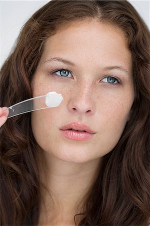 simsearch:6108-05869257,k - Woman applying moisturizer cream on her face Stock Photo - Premium Royalty-Free, Code: 6108-06906341