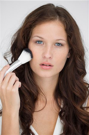 simsearch:6108-05869257,k - Portrait of a woman using make-up brush on face Stock Photo - Premium Royalty-Free, Code: 6108-06906342