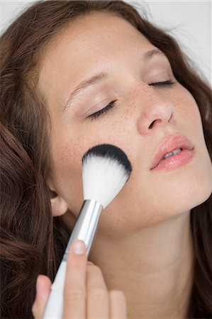 simsearch:6108-05869257,k - Woman doing make-up with a make-up brush Stock Photo - Premium Royalty-Free, Code: 6108-06906346