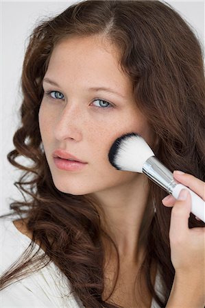 simsearch:6108-05869257,k - Woman doing make-up with a make-up brush Stock Photo - Premium Royalty-Free, Code: 6108-06906387