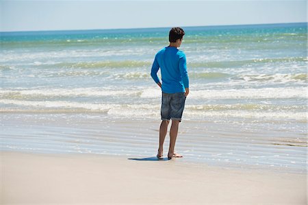 en pied - Man standing on the beach and looking at the sea Photographie de stock - Premium Libres de Droits, Code: 6108-06906302