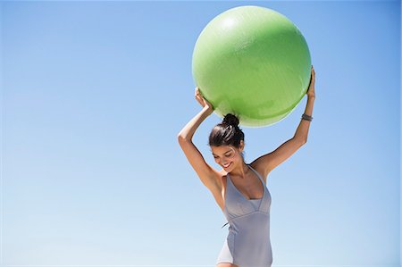 simsearch:6108-06907213,k - Beautiful woman holding a fitness ball on the beach Stock Photo - Premium Royalty-Free, Code: 6108-06906596