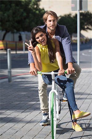 Portrait of a smiling couple riding a bicycle Stock Photo - Premium Royalty-Free, Code: 6108-06906513