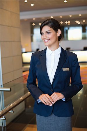 Receptionist standing in a hotel lobby and smiling Stock Photo - Premium Royalty-Free, Code: 6108-06906755