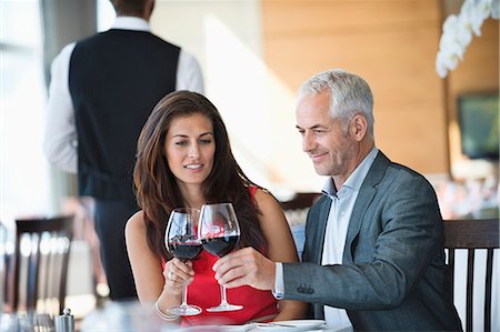 Couple toasting with wine glasses in a restaurant Stock Photo - Premium Royalty-Free, Code: 6108-06906758