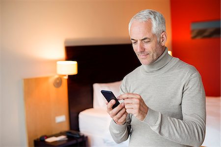 Man using a cell phone in a hotel room Stock Photo - Premium Royalty-Free, Code: 6108-06907130