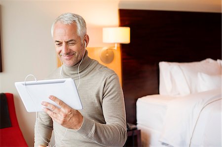 Man watching a movie on digital tablet in a hotel room Stock Photo - Premium Royalty-Free, Code: 6108-06907139