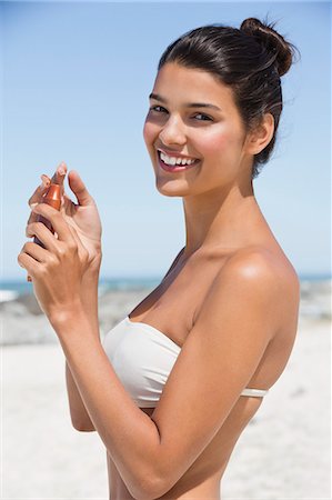 Beautiful woman holding a suntan lotion on the beach Stock Photo - Premium Royalty-Free, Code: 6108-06907287