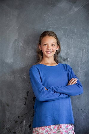 smile girl - Girl smiling with his arms crossed in front of a blackboard in a classroom Stock Photo - Premium Royalty-Free, Code: 6108-06907684