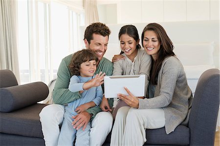 smiling families - Family looking at a digital tablet Stock Photo - Premium Royalty-Free, Code: 6108-06907608