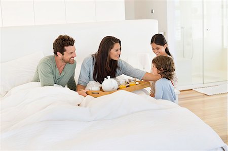 family with two children - Children serving tea to their parents on the bed Stock Photo - Premium Royalty-Free, Code: 6108-06907637