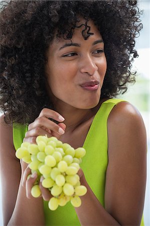 Close-up of a smiling woman eating grapes Stock Photo - Premium Royalty-Free, Code: 6108-06907798