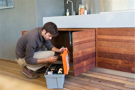 squatting man - Man repairing a kitchen sink Stock Photo - Premium Royalty-Free, Code: 6108-06907841