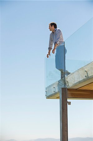 side view railings glass - Man standing on the terrace looking away Stock Photo - Premium Royalty-Free, Code: 6108-06907821