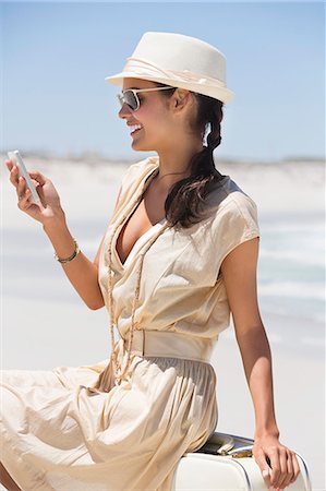 Beautiful woman text messaging on a cell phone on the beach Stock Photo - Premium Royalty-Free, Code: 6108-06907938