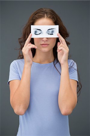 strano - Woman holding a paper with false eyes in front of her face Fotografie stock - Premium Royalty-Free, Codice: 6108-06908065