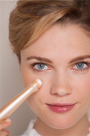 Portrait of a beautiful woman applying concealer Stock Photo - Premium Royalty-Free, Code: 6108-07969463