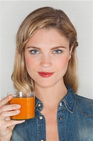 simsearch:6108-07969525,k - Portrait of a beautiful woman holding a glass of carrot juice Stock Photo - Premium Royalty-Free, Code: 6108-07969585