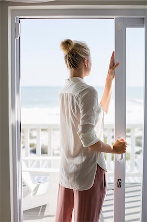 door window - Young woman standing by window at home Stock Photo - Premium Royalty-Free, Code: 6108-08662418