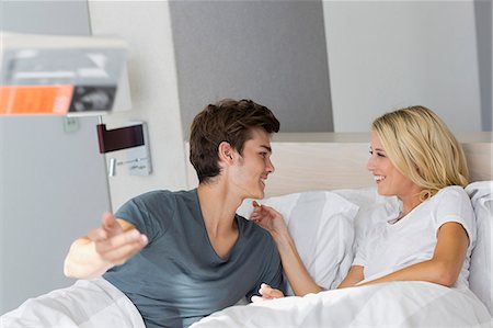 simsearch:6108-06166423,k - Young couple smiling at each other on the bed Foto de stock - Sin royalties Premium, Código: 6108-08662543