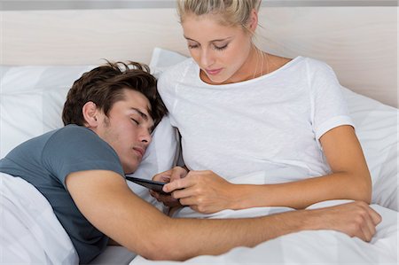 simsearch:649-01696405,k - Young woman using a digital tablet with her boyfriend sleeping near her Stock Photo - Premium Royalty-Free, Code: 6108-08662537