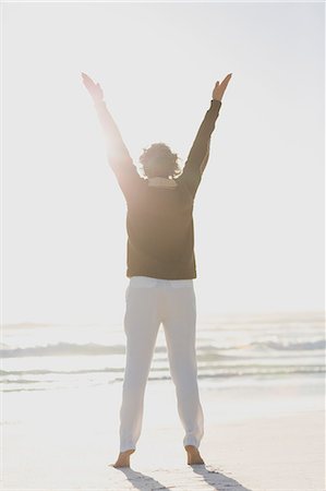 standing - Rear view of a woman standing on the beach with arms raised Stock Photo - Premium Royalty-Free, Code: 6108-08663040