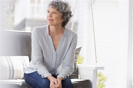 Woman sitting on a swing and day dreaming Stock Photo - Premium Royalty-Free, Code: 6108-08663166