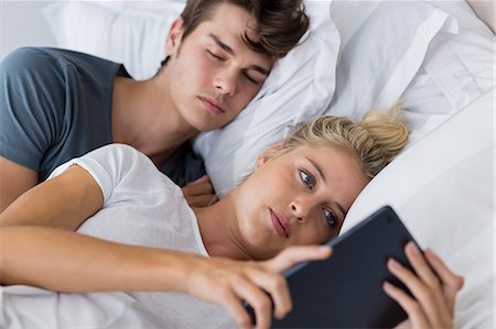 simsearch:6108-06166423,k - Young woman using a digital tablet with her boyfriend sleeping near her Foto de stock - Sin royalties Premium, Código: 6108-08663220