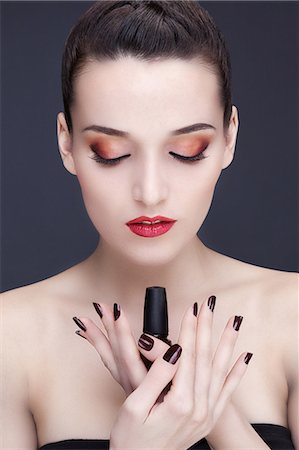 simsearch:6108-08637407,k - Portrait of a young woman holding a nail polish bottle Stock Photo - Premium Royalty-Free, Code: 6108-08637318