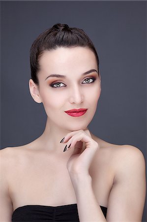 simsearch:6108-08637407,k - Portrait of a young woman smiling, hand under chin, looking toward the lens Stock Photo - Premium Royalty-Free, Code: 6108-08637323