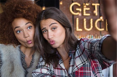 pouting (sexy look) - Portrait of happy female friends having fun in cafe Stock Photo - Premium Royalty-Free, Code: 6108-08725143