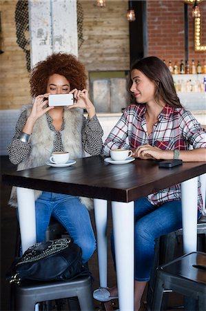 people restaurant not eye contact - Female friends taking a picture with camera phone at cafe Stock Photo - Premium Royalty-Free, Code: 6108-08725219