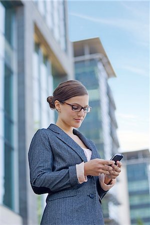 simsearch:400-04212823,k - Businesswoman walking with mobile in front of the office Stock Photo - Premium Royalty-Free, Code: 6108-08909240