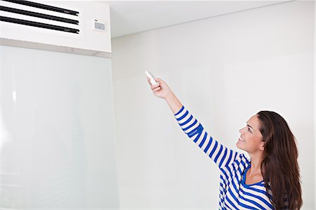 Woman controlling the air conditioning machine Stock Photo - Premium Royalty-Free, Code: 6108-08909467
