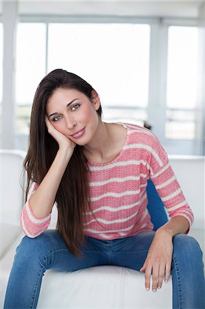 simsearch:614-01179436,k - Pretty brunette woman at the sofa looking at camera Stock Photo - Premium Royalty-Free, Code: 6108-08909769