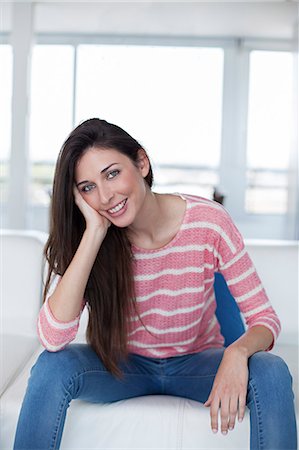 simsearch:614-01179436,k - Pretty brunette woman at the sofa smiling at camera Stock Photo - Premium Royalty-Free, Code: 6108-08909770