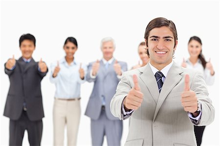 Close-up of a multicultural business team with their thumbs-up focus on a smiling man in foreground Stock Photo - Premium Royalty-Free, Code: 6109-06002668