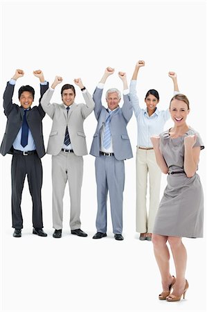 Multicultural business team raising their arms with a smiling woman clenching her fists in foreground against white background Stock Photo - Premium Royalty-Free, Code: 6109-06002634